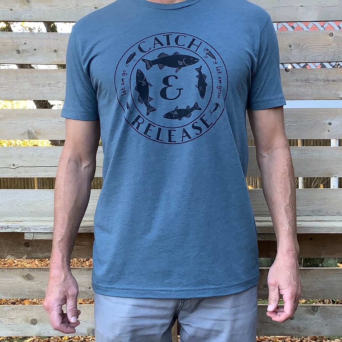 Man wearing heather indigo t-shirt with round Catch and Release fishing graphic
