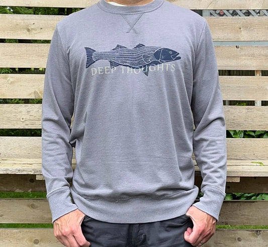 Man wearing washed heather grey crewneck sweatshirt with navy blue striped bass illustration and faded DEEP THOUGHTS text