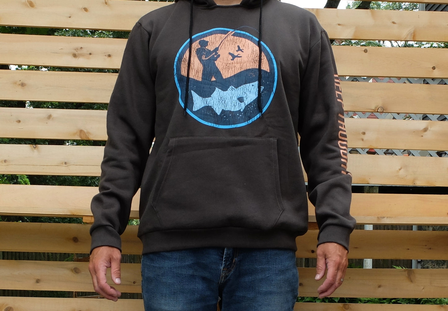 man wearing dark grey hoodie with round blue and orange surf fisherman logo