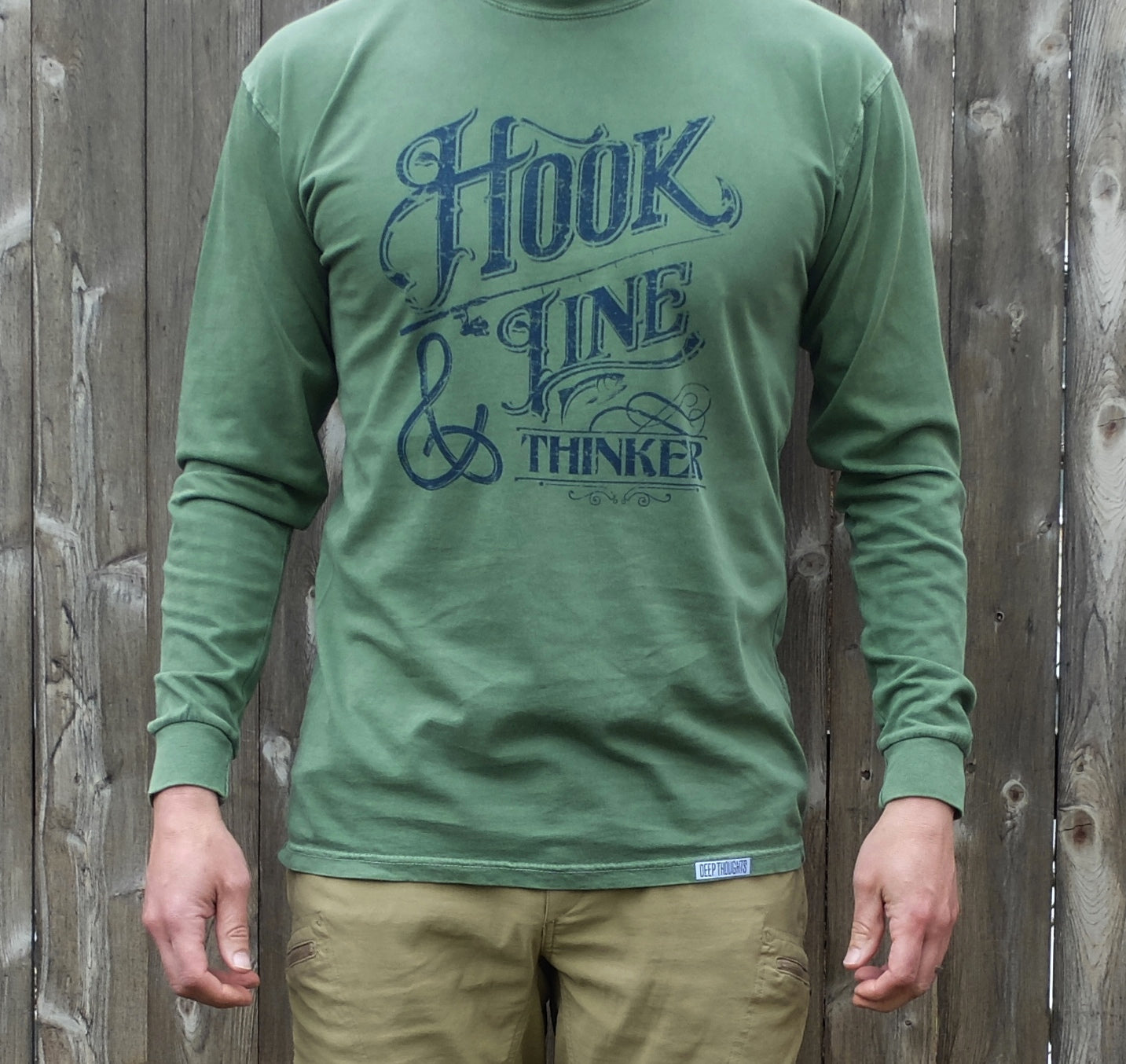 man wearing washed green long sleeve t-shirt with navy blue hook line and thinker graphic