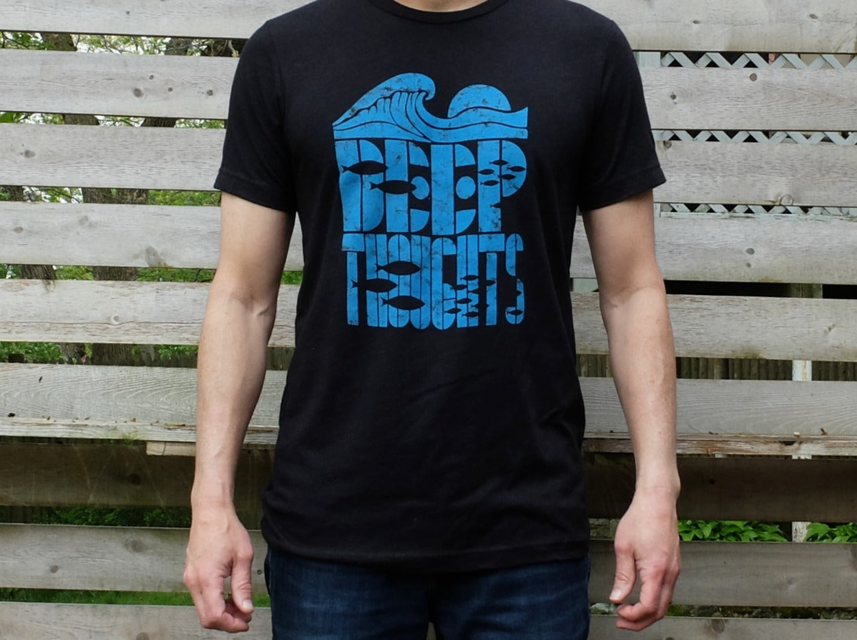 man wearing black t-shirt with bright blue cresting wave graphic over 'Deep Thoughts' text with fish silhouettes