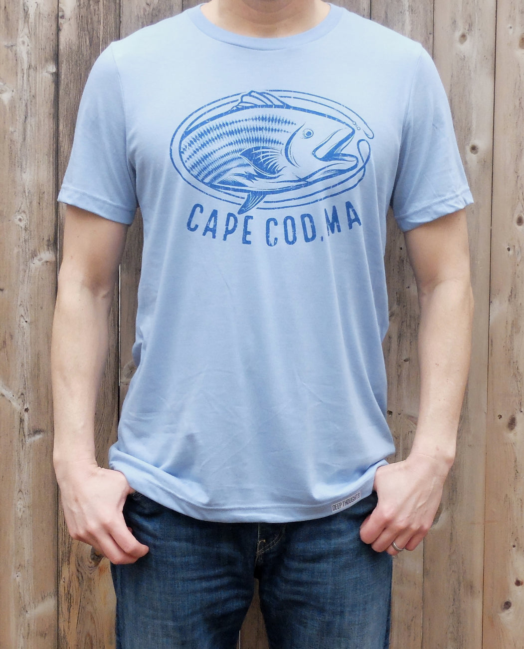 man wearing heather blue t-shirt with blue vintage style striped bass graphic and 'Cape Cod' text