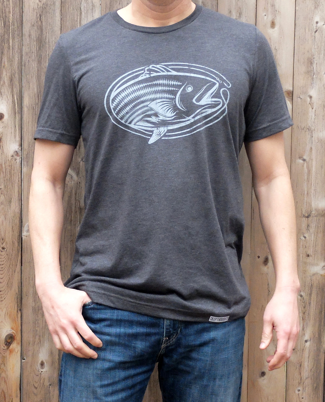 man wearing heather charcoal t-shirt with white oval-shaped striped bass fishing graphic