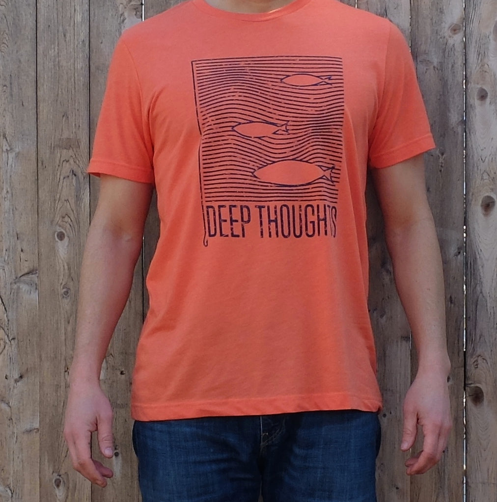 man wearing heather orange t-shirt with navy blue print showing fish swimming among wavy ocean currents