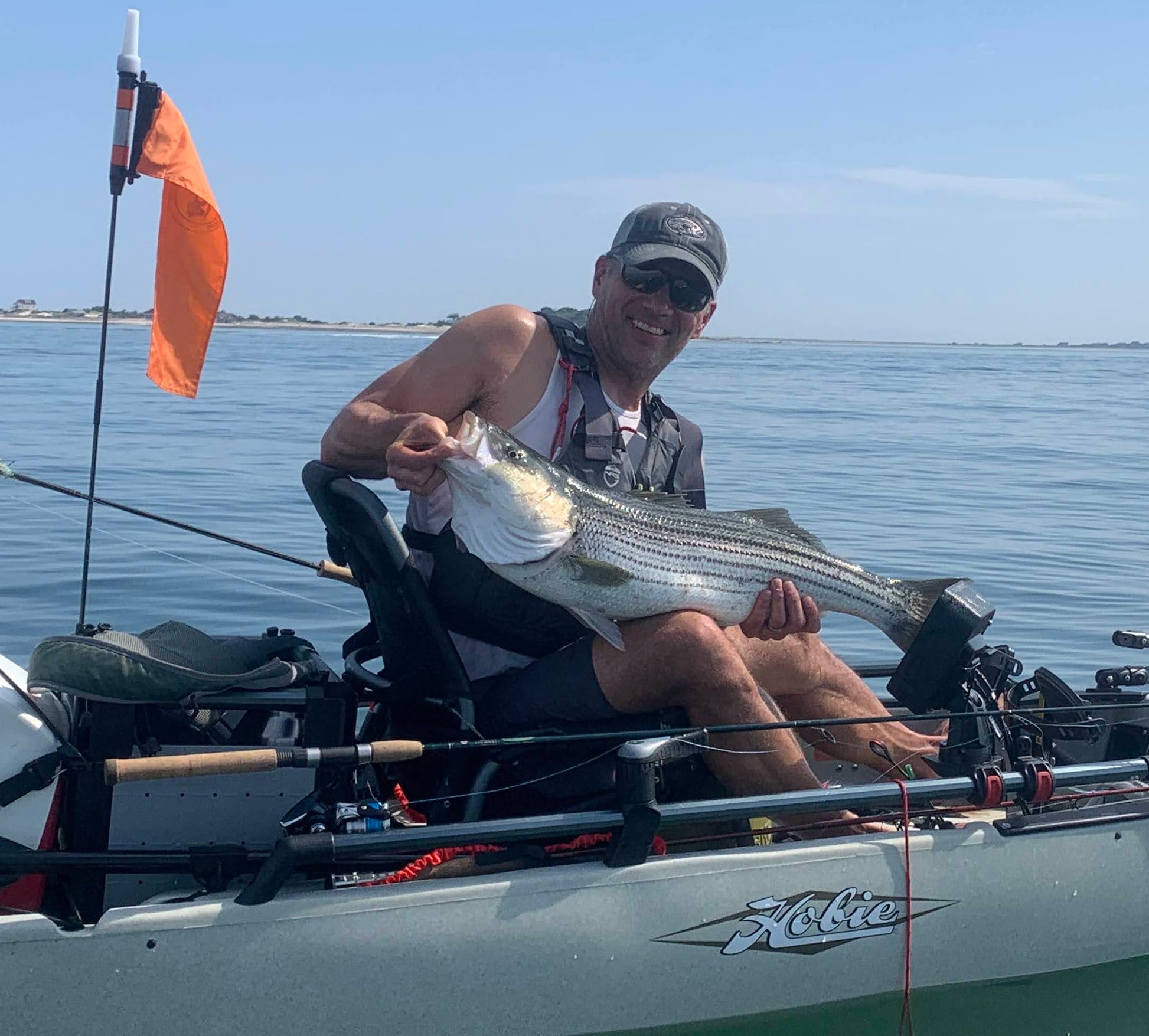 fisherman wearing charcoal and grey trucker hat with oval-shaped embroidered striped bass