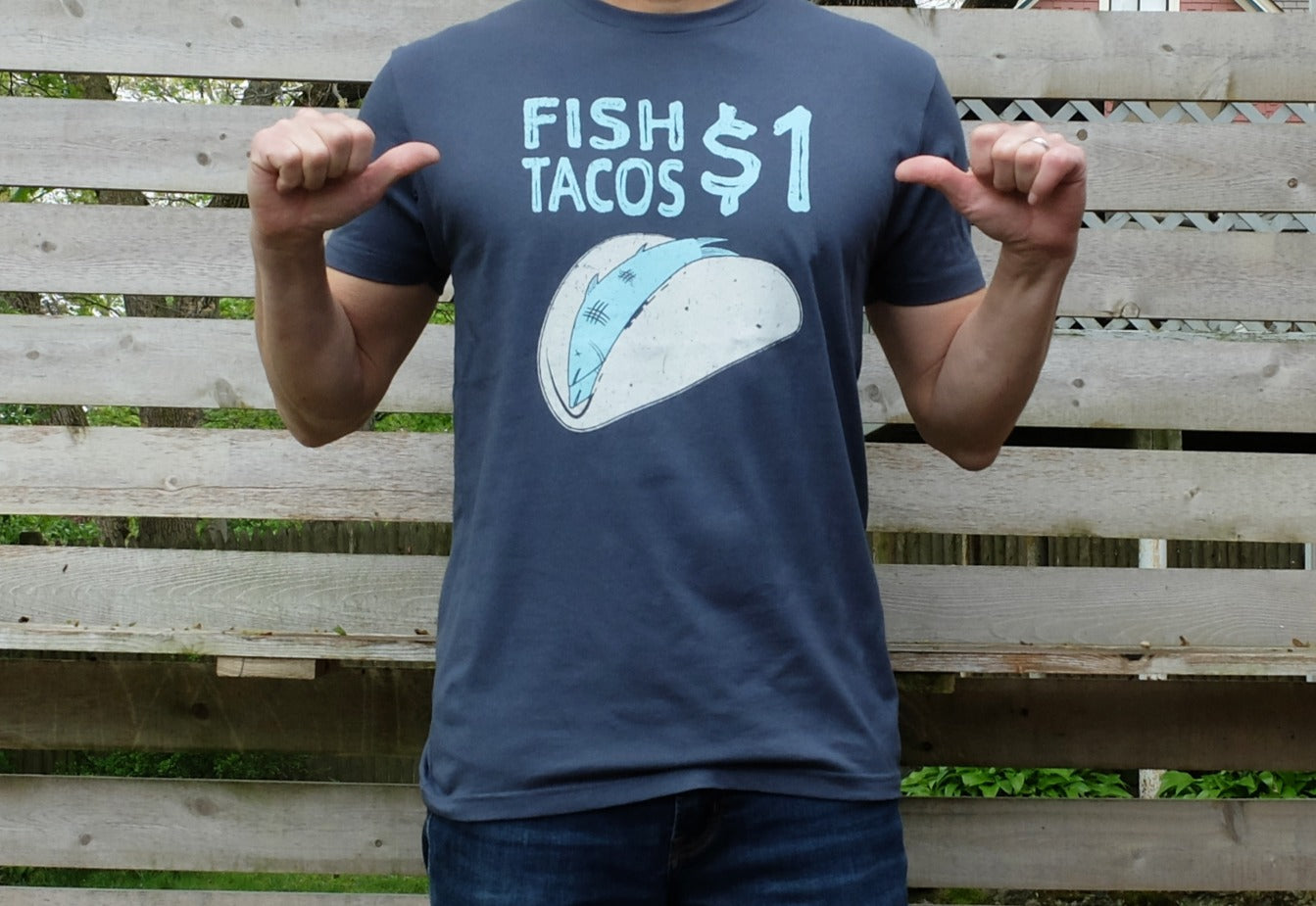 man wearing indigo blue cotton t-shirt with funny light blue and ivory one dollar fish tacos graphic