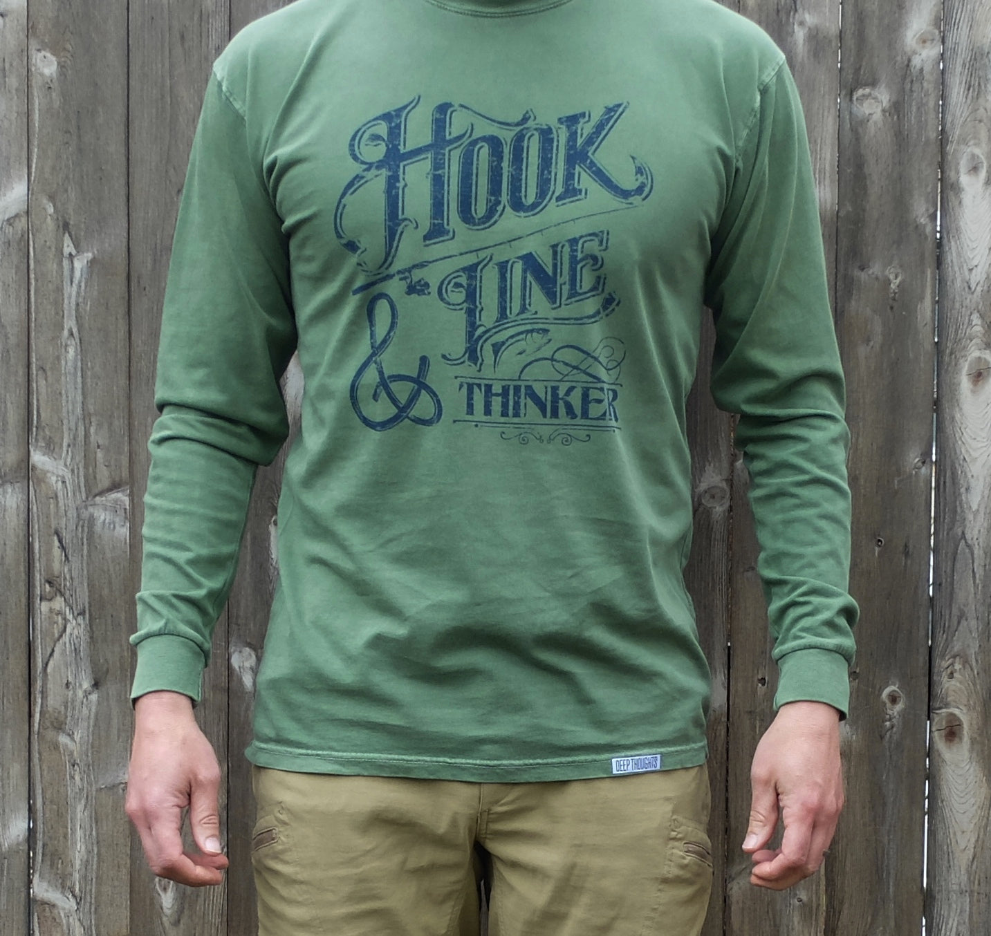 man wearing washed green long sleeve t-shirt with navy blue hook line and thinker graphic