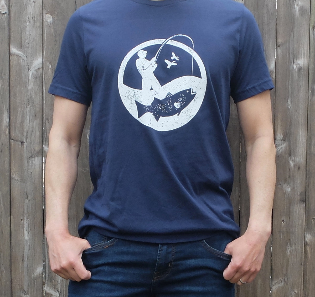 man wearing navy blue cotton t-shirt with round white surf fisherman logo