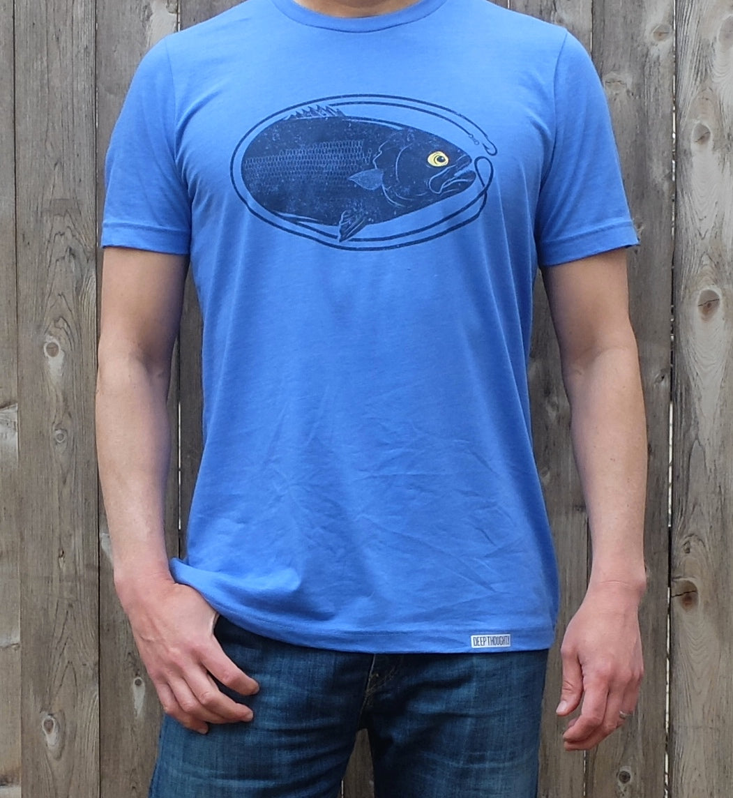 man wearing heather columbia blue t-shirt with dark blue oval-shaped bluefish fishing graphic