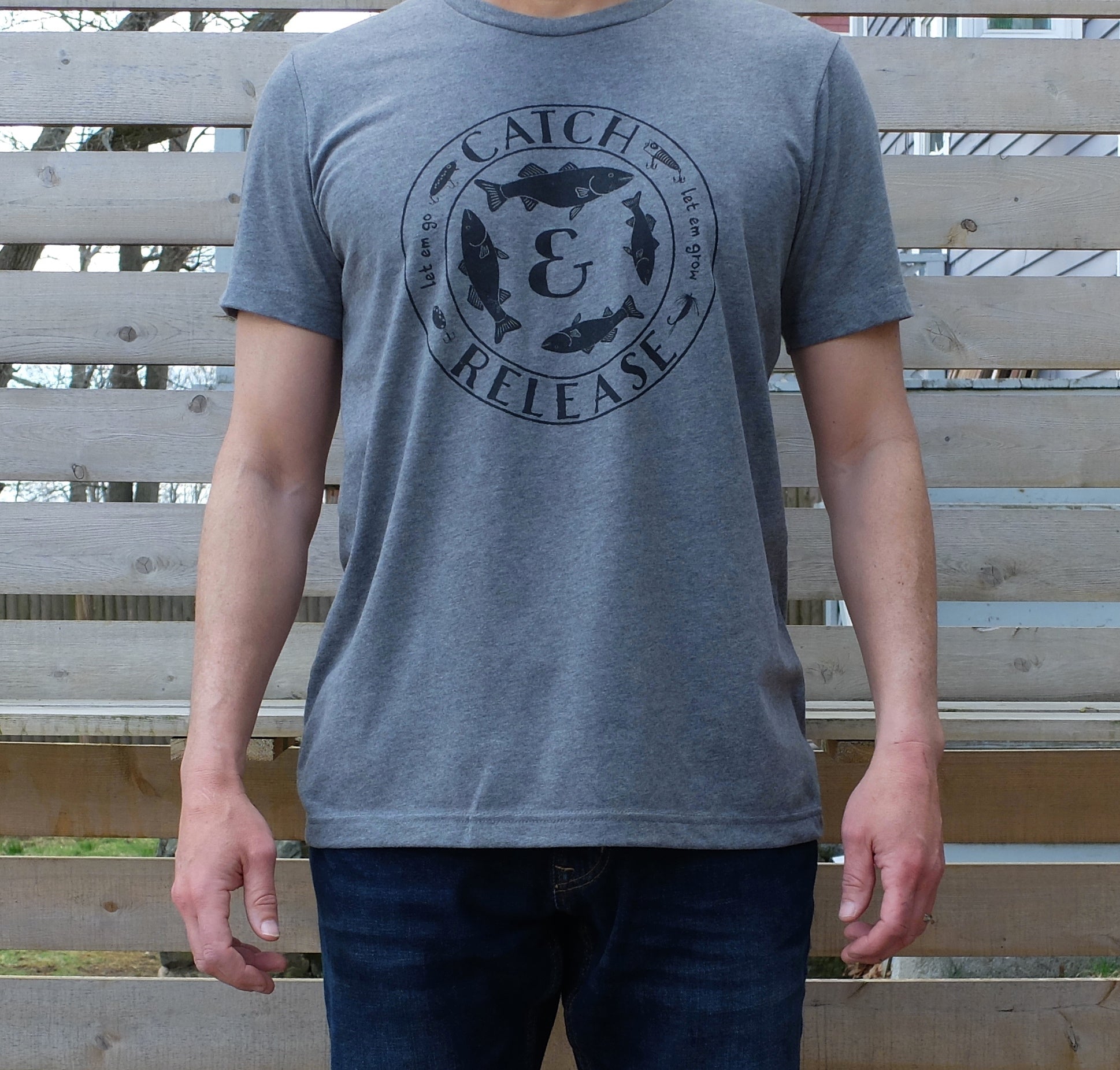 man wearing heather grey t-shirt with round vintage style 'Catch and Release' fishing graphic