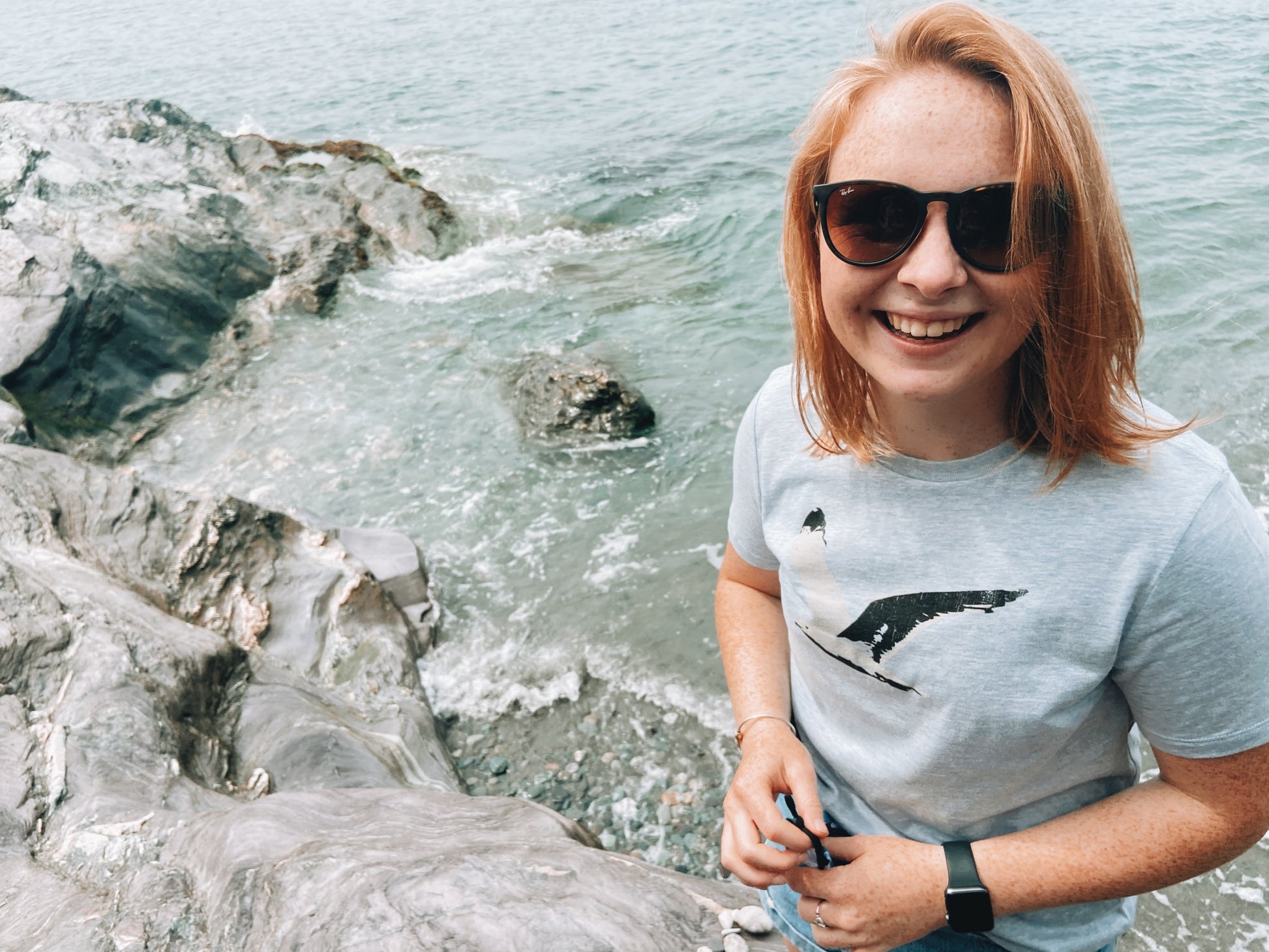 young woman wearing heather ice blue t-shirt with black and white flying seagull graphic
