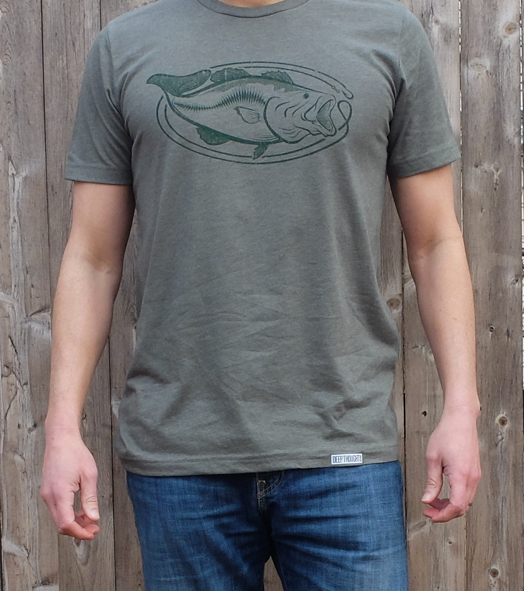 man wearing heather army green t-shirt with dark green oval-shaped largemouth bass fishing graphic